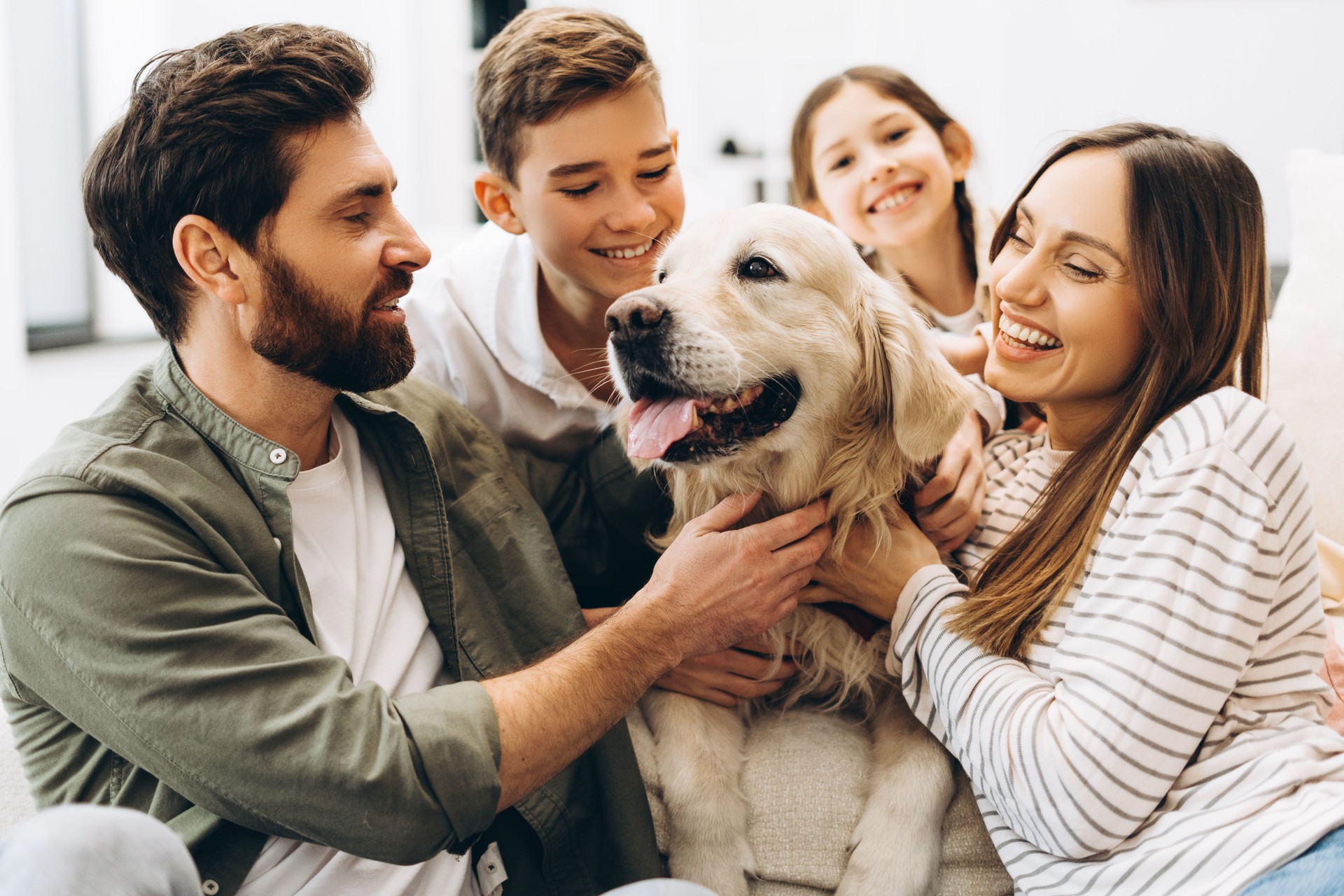 The picture of happiness - a happy family cuddling golden retriever at home